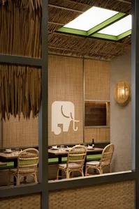 A rustic restaurant interior with bamboo walls and thatched roof.