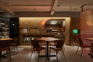A modern restaurant with stone walls and wooden tables and chairs.