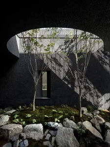 A minimalist interior design featuring concrete walls and a moss-covered floor with a small window and unique architectural e