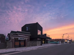 A modern black house with a glass facade at sunset