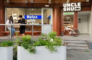 Coffee shop interior with wooden walls, glass partitions, and plants