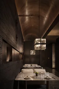 A restaurant interior featuring industrial design elements with dark concrete walls and a dark tile floor.