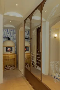 A modern pizza oven room with a dome-shaped oven, stacked wood, and tile floors.