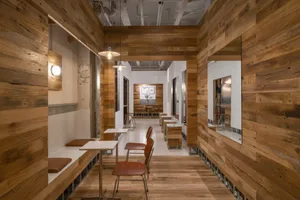 Interior of a cafe with wooden walls, tables, and chairs.