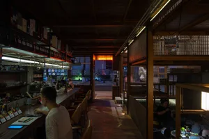 A dimly lit restaurant bar with wooden decor and seating.