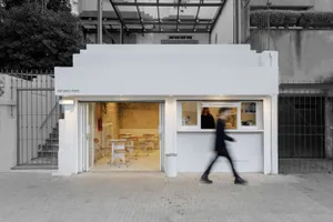 A minimalist cafe with a white interior and large glass windows.