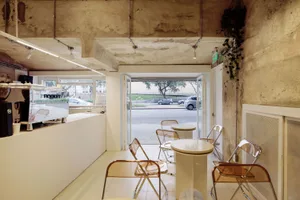 Modern coffee shop with minimalist design featuring concrete walls and floors.