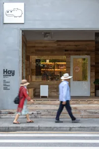 A modern coffee shop exterior featuring wooden paneling, concrete, and tile.