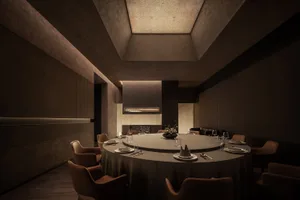 Modern restaurant interior with circular table, chairs, and concrete walls and ceiling.