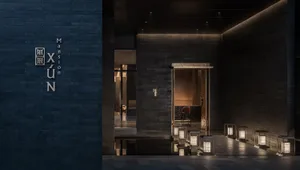 A modern restaurant entryway featuring dark brick walls with a minimalist design.