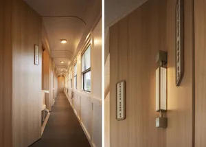 A modern private room corridor with wooden walls and floor, featuring numbered signs indicating private rooms and sconce ligh