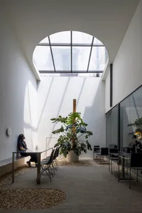 A modern office lounge featuring concrete, glass, and wood materials.