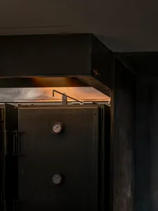 A close-up of an industrial-style kitchen with a metallic door featuring gauges.