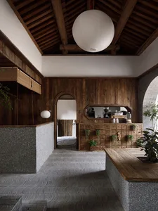 Traditional Chinese-style architecture with wooden columns, concrete walls, and wooden table and chairs.