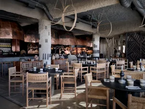 Restaurant interior with natural materials, including wooden tables and chairs, stone flooring, and copper accents.