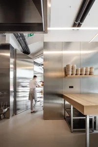 A modern commercial kitchen with stainless steel appliances and countertops, featuring sleek design and efficient layout.