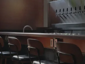 Industrial-style bar counter with metal frame, featuring wooden stools and a modern industrial design