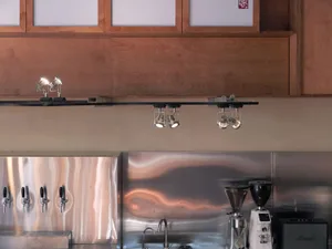 An industrial bar area with metal counter, light fixtures, and coffee brewing equipment.