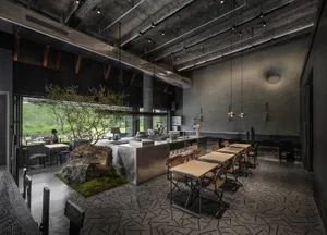 A modern industrial cafe interior with concrete walls, exposed beams, and a large tree in a planter.