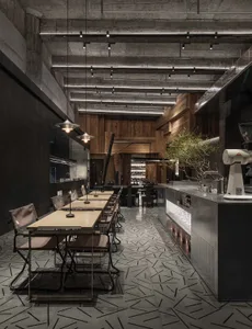 工業風餐廳室內，裸露混凝土牆面搭配木質餐桌。