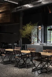 Industrial-style restaurant interior with metal accents, concrete walls, and wooden tables and chairs.
