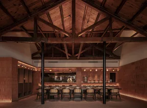 Industrial restaurant interior with wooden beams and tables.
