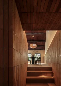 A modern dining room features wood-paneled walls and a glass-top table.