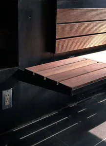 A wooden window shade mounted on a black wall, showcasing its sleek and contemporary design.
