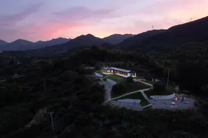 Vacation home with clay dome structures and a glass exterior, surrounded by greenery and mountains.