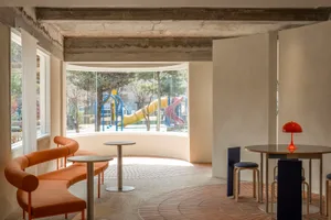 A modern cafe interior featuring concrete flooring and stainless steel tables and chairs.