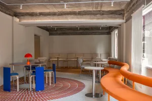 Modern cafeteria with concrete ceiling, brick floor, and fabric seating.