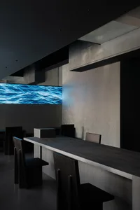 Minimalist restaurant interior featuring concrete walls and a large water display