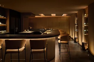 Modern restaurant bar interior with wooden materials and warm lighting.