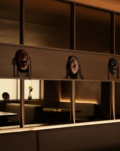 A wooden interior restaurant with traditional masks hanging on the wall.