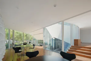 An indoor space with modern design features including glass walls and wooden flooring.