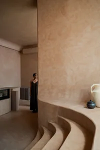 A minimalist interior space featuring concrete walls and steps, with a person standing in the background.