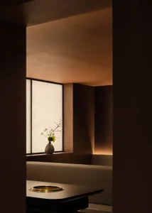 A minimalist restaurant booth featuring wooden seating and paper walls.