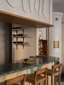 Modern restaurant interior with a polished marble counter and wooden bar stools.