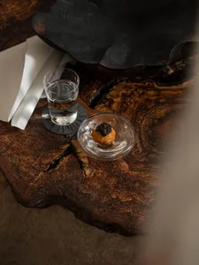 A wooden table topped with a bowl of food and a glass of water.