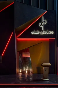 Modern nightclub exterior with metallic accents, glass panels, and LED lighting at night.