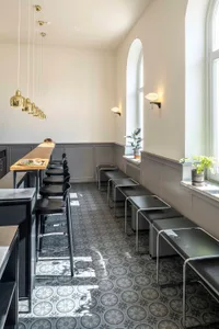 Industrial-style cafe with concrete floor and keramik tile, featuring black seating and modern furniture.