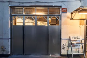 A metal storefront with an industrial design style, featuring large glass panels and a rustic exterior.