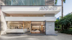 A minimalist coffee shop with large glass windows and concrete exterior, featuring modern furniture and decor.