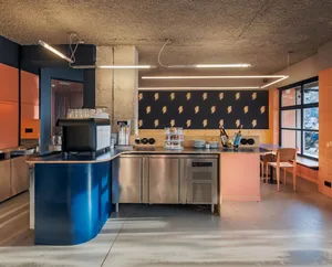 Modern cafe kitchen with metal counter, industrial-style lighting, and lightning bolt wallpaper.