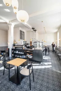 Modern coffee shop with black furniture and patterned concrete tiles