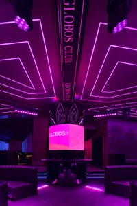 A modern nightclub interior with purple lighting and a central display.