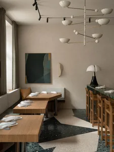 A modern restaurant interior featuring a contemporary design with terrazzo flooring, wooden tables, and minimalistic decor.