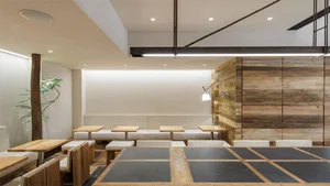A contemporary restaurant interior with wooden furniture and concrete flooring.