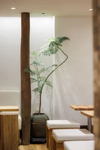 A modern, minimalist restaurant with wood and concrete furniture and a leather padded lounge.