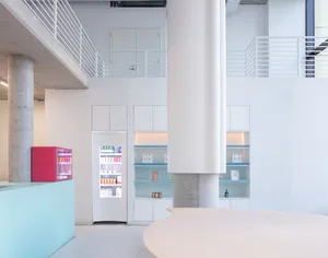 A modern, minimalist interior design with white walls, concrete pillars, glass shelves, and white furniture.